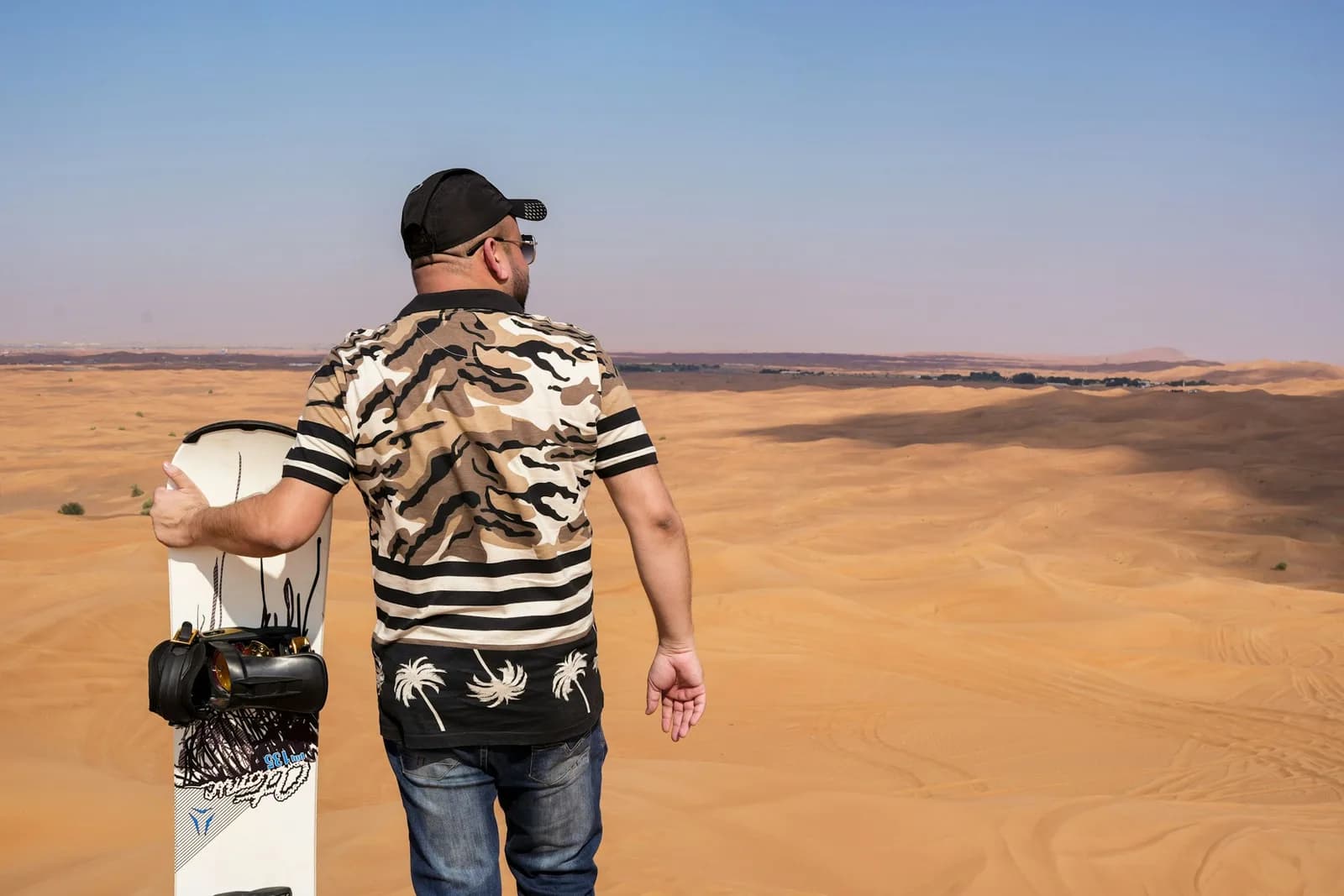 Sandboarding down a steep dune in the Dubai desert — photo 1