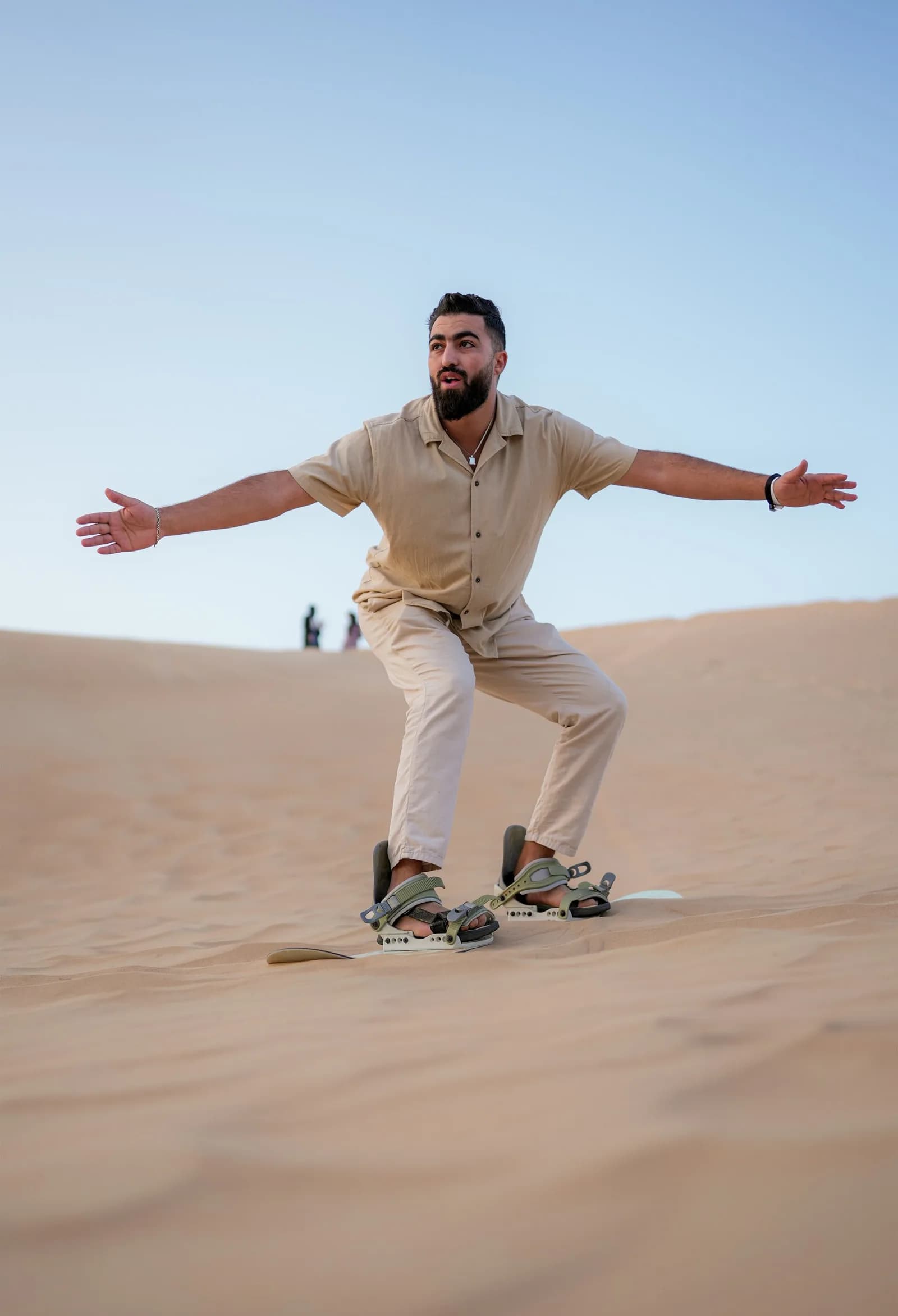 Sandboarding down a steep dune in the Dubai desert