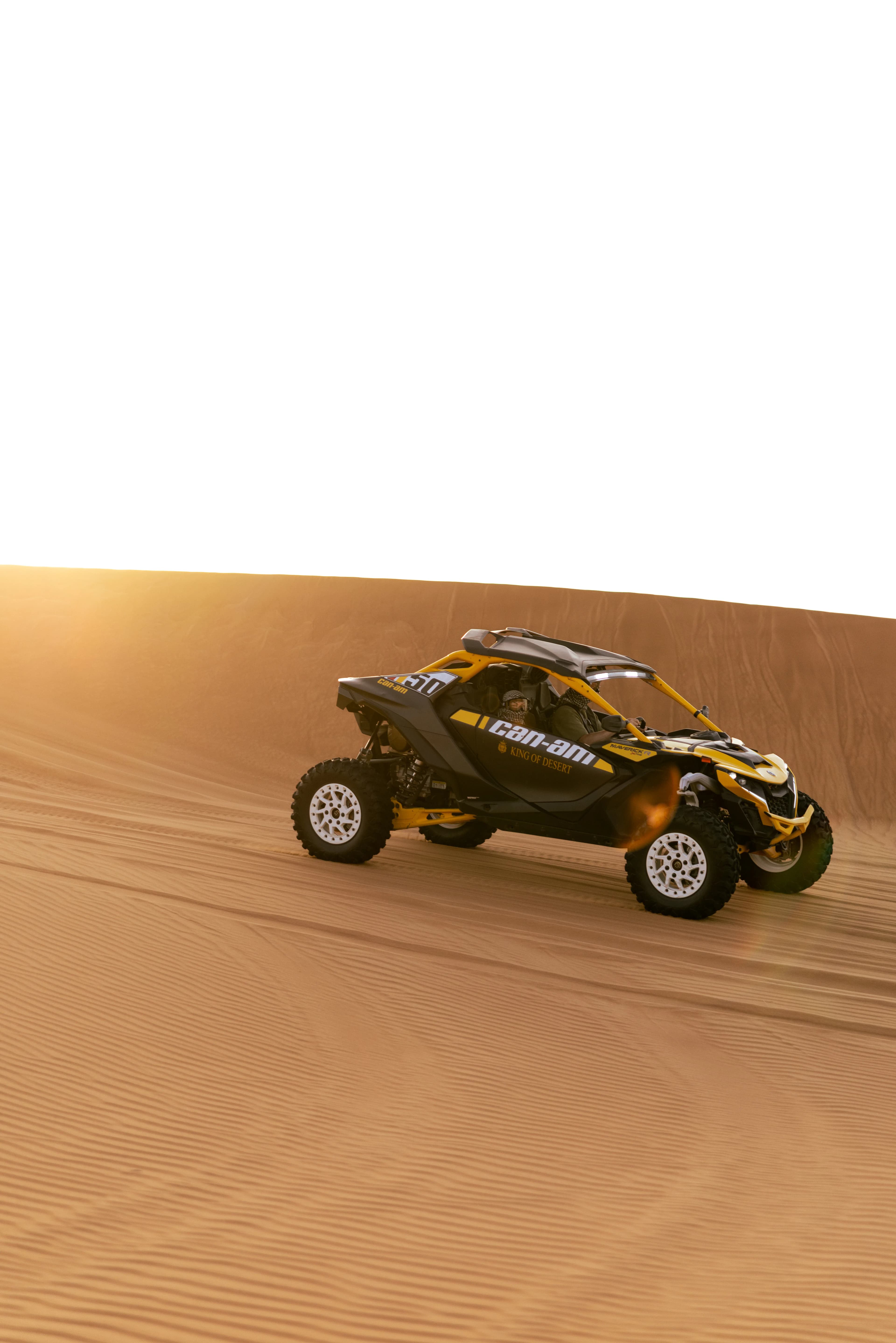 Can-Am Maverick R climbing a red dune at sunset near the camp