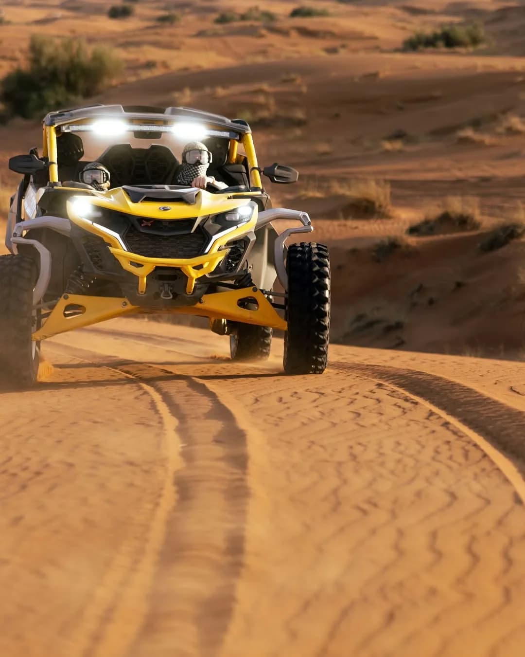 Can-Am Maverick R dune buggy driving head-on across red Dubai desert dunes